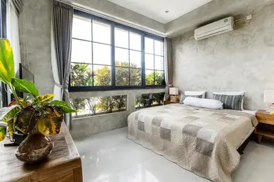 a bedroom with a large bed and large windows at DUUR Apartments in Seminyak