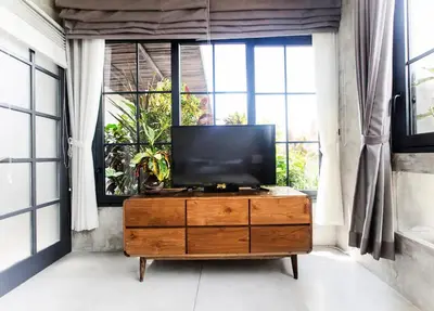 a television on a dresser in a room with windows at DUUR Apartments in Seminyak
