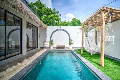 a swimming pool in the backyard of a house with a swing at Villa Esha III in Seminyak