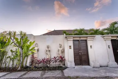 a white house with statues on the side of it at Villa Music in Seminyak