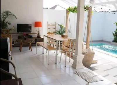 a living room with a table and a swimming pool at Villa Music in Seminyak