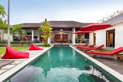 a villa with a swimming pool and red umbrellas at Alarte Estate by Villa Finder in Seminyak