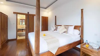 a bedroom with a large bed with a wooden frame at Alarte Estate by Villa Finder in Seminyak