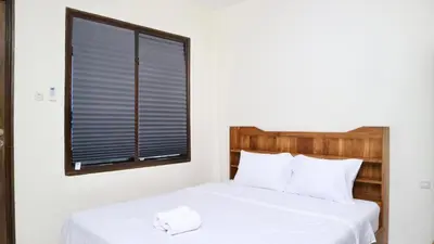 a bedroom with a white bed with a window at Puri Beach Inn - Poppies 2 in Legian