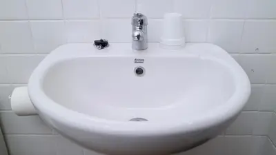 a white sink in a white tiled bathroom at Puri Beach Inn - Poppies 2 in Legian