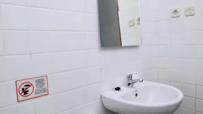 a white bathroom with a sink and a mirror at Puri Beach Inn - Poppies 2 in Legian