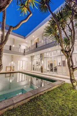 a large house with a swimming pool and palm trees at Villa Kamboja 1 Seminyak in Seminyak