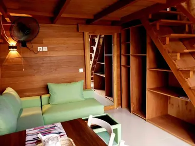 a living room with a green couch and some shelves at Thula Thula Bali Villas in Kerobokan