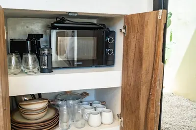 a cupboard with a microwave and some dishes at Casa Admire Villas in Legian
