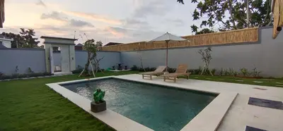a swimming pool in a yard with an umbrella at The Lebak Sari Guesthouse in Umalas
