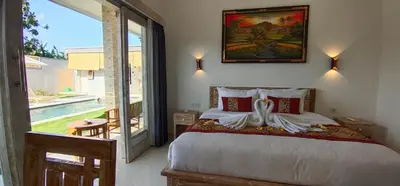 a bedroom with a large bed and a large window at The Lebak Sari Guesthouse in Umalas