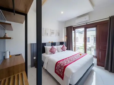 a bedroom with a large bed with red and white pillows at De Amelia Villa Seminyak by Nagisa Bali in Seminyak