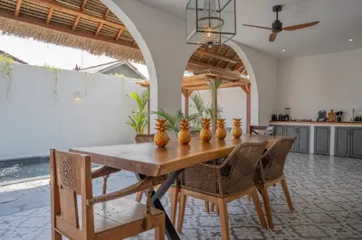 a dining room with a wooden table and chairs at Villa Rhapsody Seminyak in Seminyak