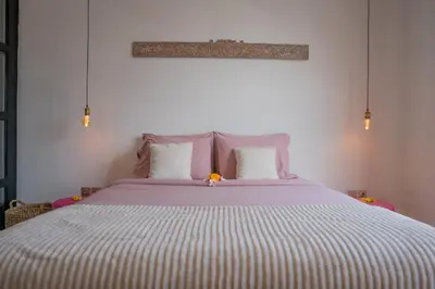a bedroom with a large bed with a striped blanket at Villa Rhapsody Seminyak in Seminyak