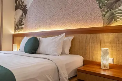 a bedroom with a large bed with a wooden headboard at Cove Vin Stay in Sanur