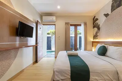 a bedroom with a large bed with a flat screen tv at Cove Vin Stay in Sanur