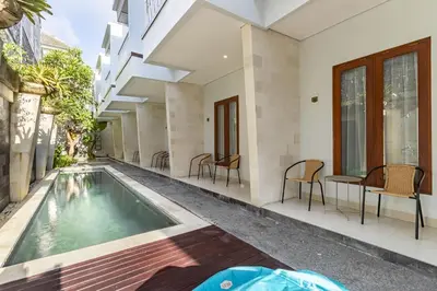 a swimming pool in a building with chairs around it at Cove Vin Stay in Sanur