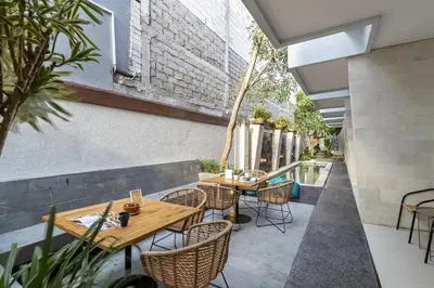 an outdoor patio with tables and chairs and a pool at Cove Vin Stay in Sanur
