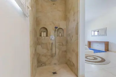 a shower in a bathroom with a stone wall at 3 bedr Mediterranean vibes private pool 5min beach in Seminyak