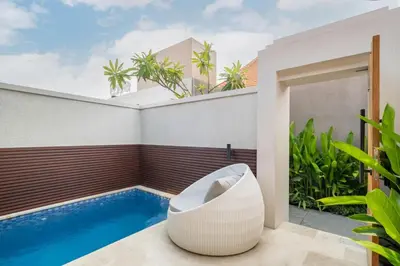 a room with a swimming pool and a white chair at Cove Anantaha Loft & Villa in Seminyak