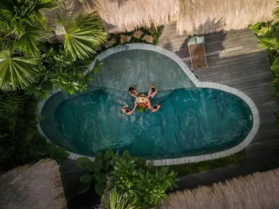 an overhead view of a man swimming in a swimming pool at Villa Belle Oasis - Next To Canggu 5BR Tropical Paradise with Private Pool & Stunning Rice Field Views in Kerobokan