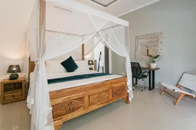 a bedroom with a canopy bed and a desk at 2 villa complex near Atlas beach in Canggu