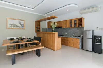 a kitchen with a wooden table and a refrigerator at 2 villa complex near Atlas beach in Canggu