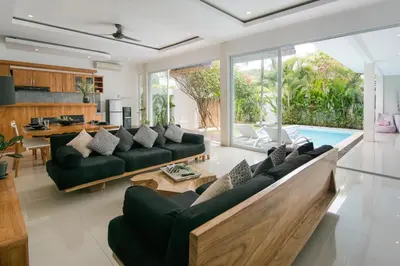 a living room with black couches and a pool at 2 villa complex near Atlas beach in Canggu