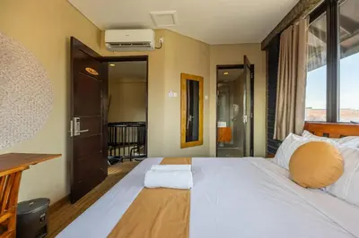 a bedroom with a large bed with a large window at Cove Kavana in Canggu