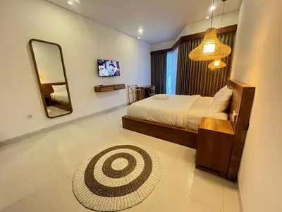 a bedroom with a bed and a mirror and a rug at Braban Sari Bali in Seminyak
