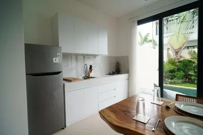 a kitchen with a wooden table and a refrigerator at Canggu Zen Villa - 2 BR Villa in Berawa in Canggu