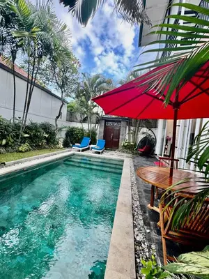 a pool with a table and a red umbrella at Bby Diamond Villa in Seminyak