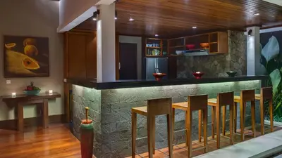 a bar in a house with wooden floors and chairs at Villa Asta in Seminyak