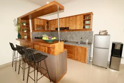 a kitchen with wooden cabinets and a refrigerator at 3 neighbour villas 3 pools near Atlas Beach Club in Canggu