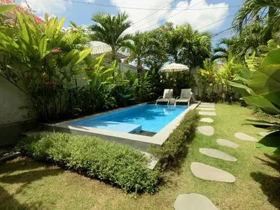 a swimming pool in a garden with chairs and plants at 3 neighbour villas 3 pools near Atlas Beach Club in Canggu