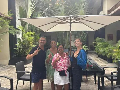 a group of people standing under an umbrella at SURFARIS INN on poppies 2 in Legian