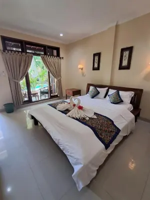 a bedroom with a large bed with a large window at SURFARIS INN on poppies 2 in Legian