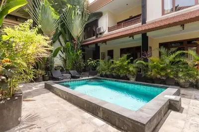 a swimming pool in front of a house with plants at SURFARIS INN on poppies 2 in Legian