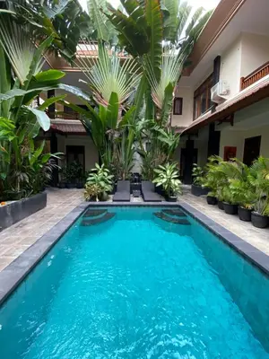 a swimming pool in front of a house with plants at SURFARIS INN on poppies 2 in Legian