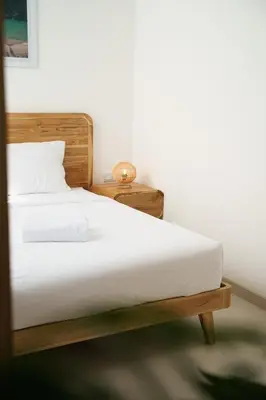 a bedroom with a white bed and a night stand at Mau Villa by Bali Bliss Properties in Canggu