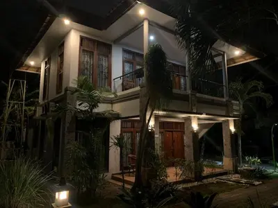 a house with a lot of plants in front of it at Villa D Lima Top Floor in Kuta