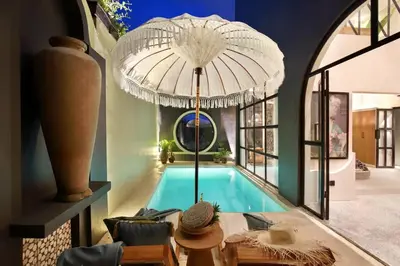 a house with a swimming pool with a large umbrella at Casa Ghitani Kerobokan 1 Bed Enclose Living room WH2 in Umalas