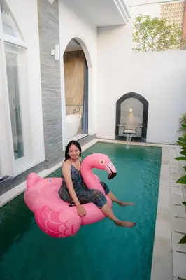 a woman sitting on a pink flamingo in the water at Dikubu Bali Villa and Suites in Kerobokan