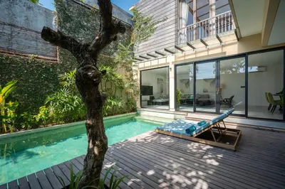 a house with a pool and a tree next to it at Villa Biku in Umalas