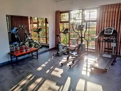 a gym with exercise bikes and a table and windows at 3 Bd Pvt House with big common pool and Gym in Nusa Dua
