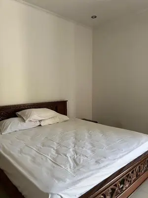 a bedroom with a bed with white sheets at Pondok Ledog 01 in Badung