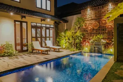 a pool in the backyard of a house with two chairs at Shira House Bali in Legian