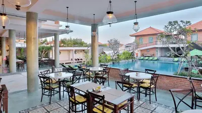 an outdoor patio with tables and chairs and a swimming pool at SOLTERRA SEMINYAK Boutique Hotel & Spa Powered by Archipelago in Seminyak