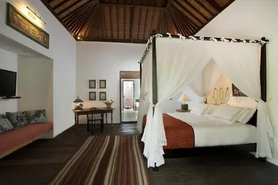 a bedroom with a canopy bed and a table at Villa MAMOUNE in Canggu