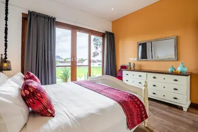 a bedroom with a bed and a dresser with a mirror at Athos Villa by iBali Management in Seminyak